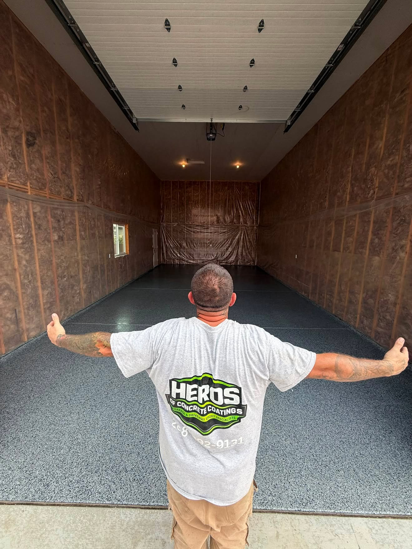 Heros of Concrete Coatings crew member standing in a finished blue flake garage